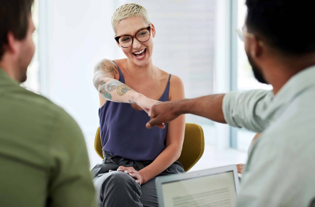 Smiling woman engaging in group therapy session, showing peer support and connection during addiction recovery at California Detox & Recovery Center.