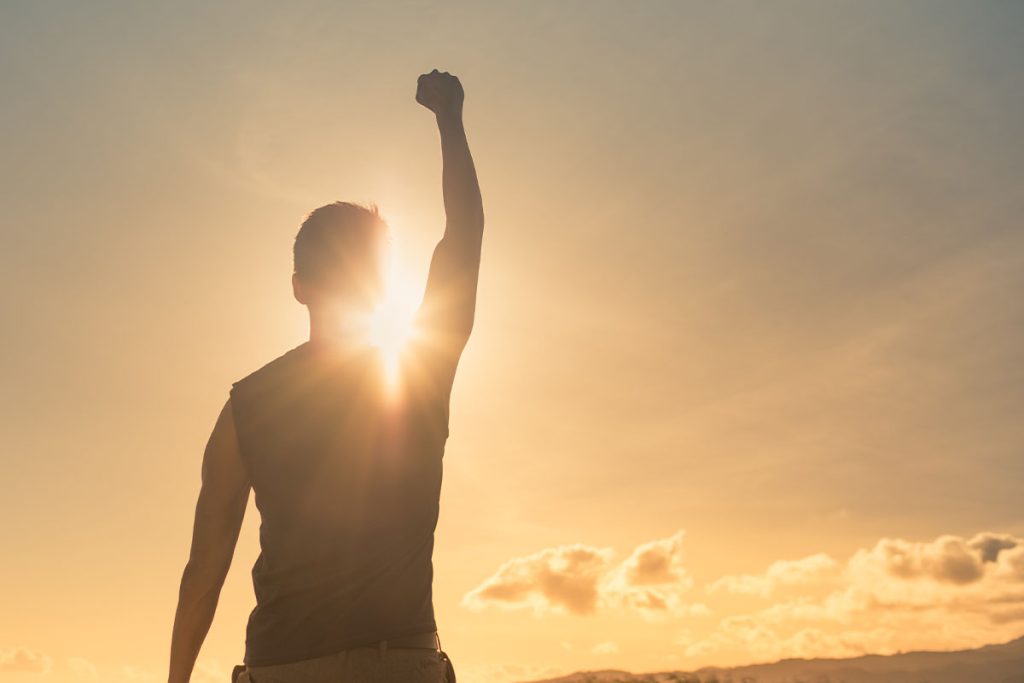 Man golding up his arm with a fist in front of the sun representing addiction recovery at California Detox & Recovery Center in Los Angeles.