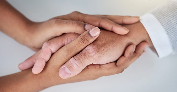 Close up of hands being held together with a white background representing healing during a family therapy session at California Detox & Recovery Center in Los Angeles.