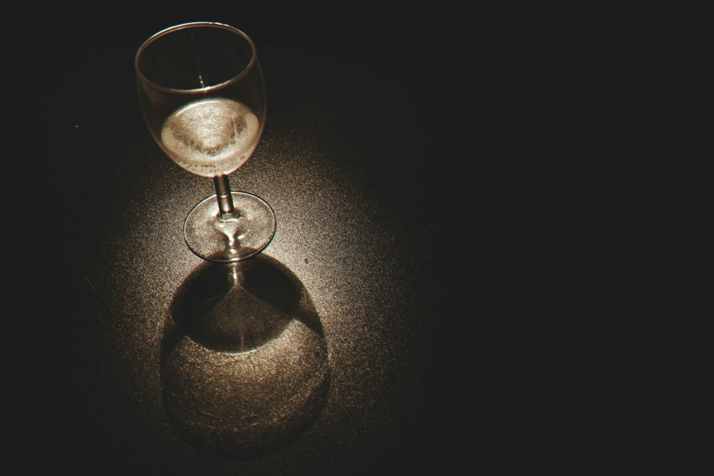 Wine glass on a dark surface under spotlight, symbolizing alcohol addiction in Los Angeles and recovery support at California Detox & Recovery Center.