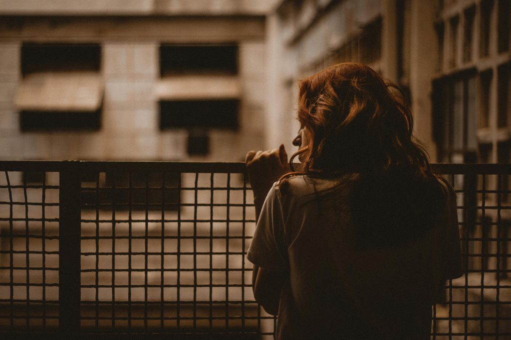 Girl holding onto a fence struggling with methamphetamine addiction in los angeles.