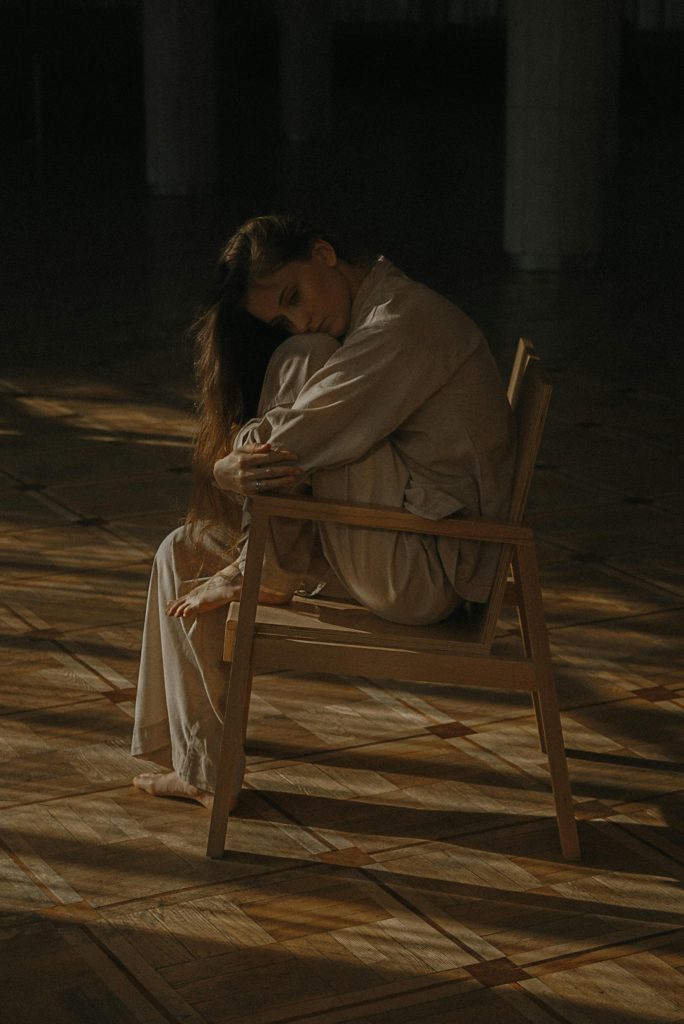 Woman sitting on a wooden chair despair struggling with opioid addiction.